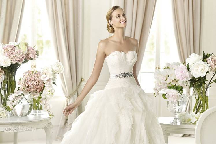 BENICARLOFeathers, beading and a wide skirt are modern design details that make Benicarlo by Pronovias 2013 so spectacular. Made of tulle, the waist-hugging bodice is softly draped and adorned with white feathers that accentuate the beauty of the sweetheart neckline. The waist is cinched and emphasized by a vintage-style embroidered belt. The chiffon shirt is created with a myriad of tulle layers, providing volume while maintaining a light and lively appearance.