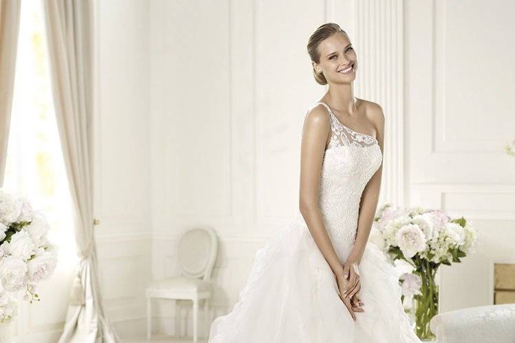 ULMENUlmen by Pronovias 2013 has an unmistakably modern style. Made in soft tulle and delicate organza, this wedding dress has an original asymmetric neckline and a cornelli bodice with beautiful beaded details. The skirt of this princess dress is made of circular frills.