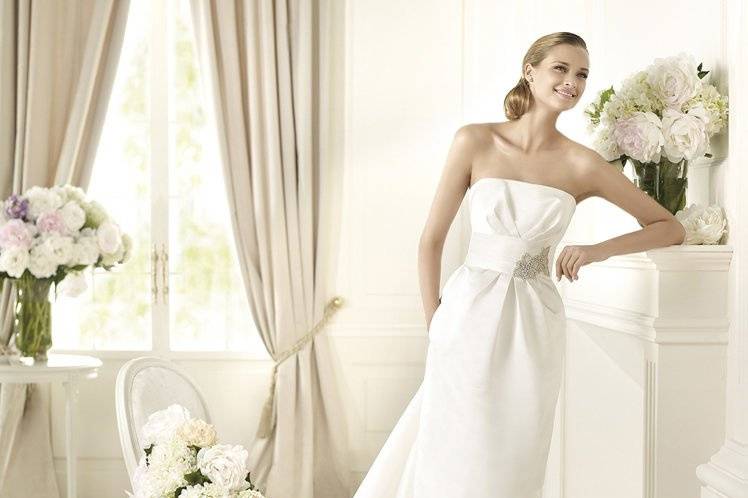 DAKARThe clean, simple lines of the Dakar model from the Pronovias 2013 collection give it elegant character. This straight wedding dress enhances the figure with its delicate folds that add flattering volume at the hip. The bodice has an elegant strapless neckline and folds embellished by a soft satin sash with spectacular gemstone embroidery. The dress flows features an elegant skirt with a marvellous train that fans out from the sash at the waist.