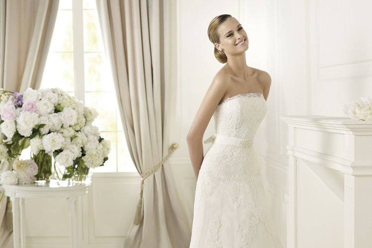 DANESAElegant brides will find everything they have ever dreamed of in the Danesa model from the Pronovias 2013 collection. This lace over tulle creation has very restrained lines. The strapless neckline has an original tulle edging that echoes the lace on the skirt and bodice. A narrow belt encircles the waist, finishing in a bow at the back and has elegant embroidery at the front.