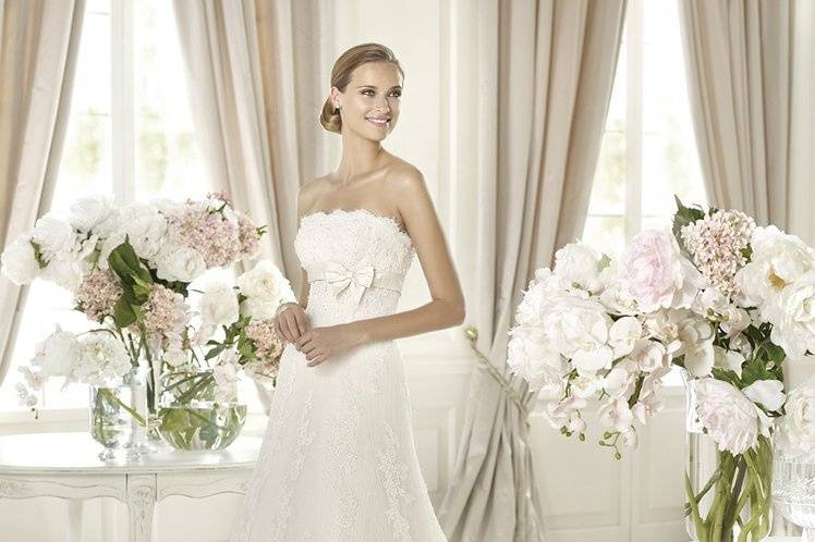 GOMERAGomera by Pronovias 2013 is a refined, elegant gown with all the romantic beauty you dream of for your big day. This flattering empire waist wedding dress has a strapless neckline edged with wonderful lace. The gemstone embroidery on the lace and delicate silk band that encircles the bodice make this dress shimmer. Beautiful lace flows down a classic skirt creating spectacular shapes that finish in stunning waves of lace.  The finishing touch to a dress that enhances the bride's shape, softening her waist and hips.