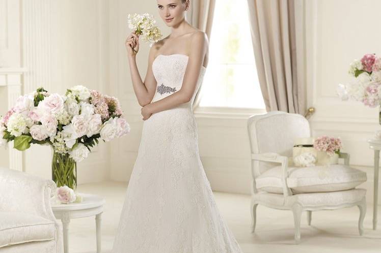 its unforgettable romantic style has been designed with a flattering sweetheart neckline and lovely scallops. A wonderful grosgrain belt with delicate silver beading emphasizes the waist of this A-line wedding dress. The romantic skirt ends in a beautiful wave at the hem.