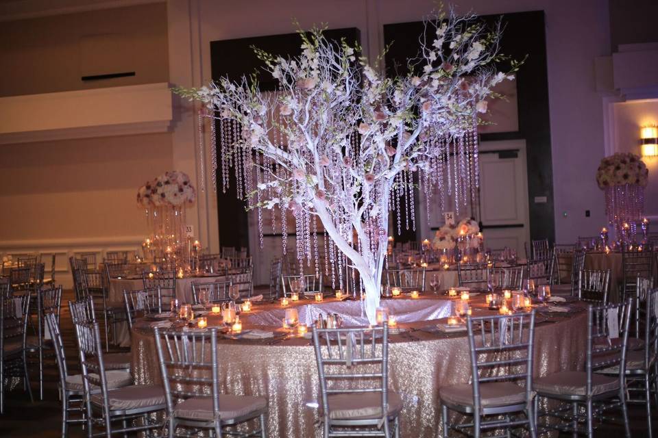 Oversized round table with a lit with lots of crystals hanging manzanitas tree emerging from the center