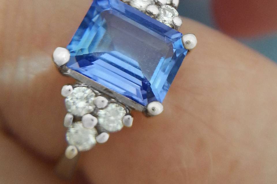 Vintage style engagement ring with a natural light blue emerald cut sapphire.