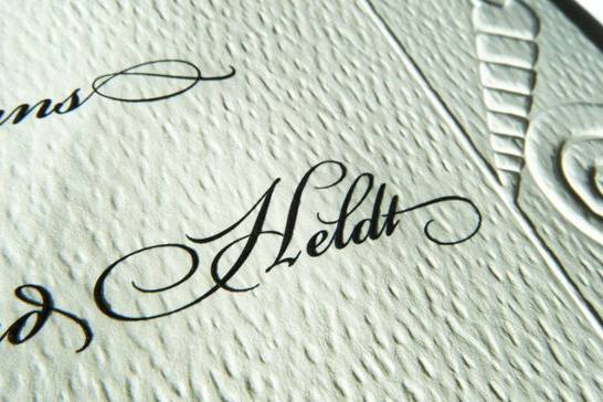The combination of engraved type and embossed graphics on a textured paper give this invitation a lush, luxurious look.