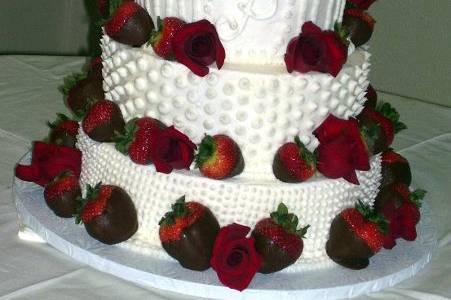 This is a Fresh Strawberry Cake with chocolate covered strawberrys and red roses on a buttercream icing