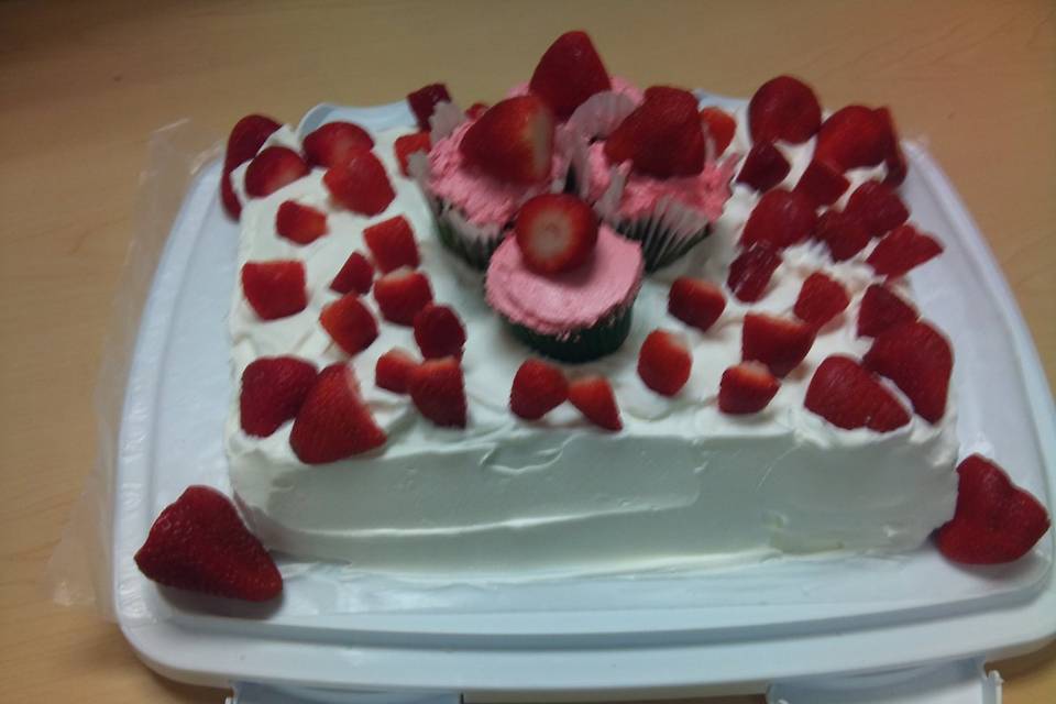 Strawberry Shortcake consisting of a Chocolate flavored cake bottom layer, then a Strawberry Creme filling, then a Vanilla cake layer.  The entire cake is surrounded in whipped cream then topped with Vanilla Nut cupcakes surrounded with strawberries.