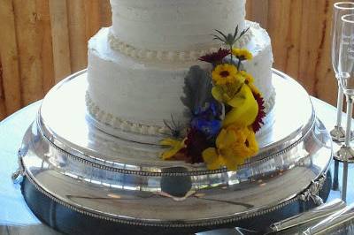 Wedding cake decorated with viking poms, delphinium, thistle, and hypericum at Old House Vineyard