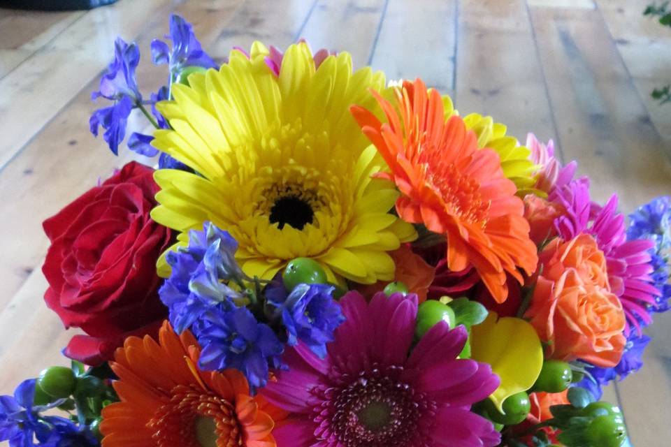 Fun mix of gerbera daisies, green hypericum berries, yellow calla lilies, orange spray roses, seeded euc. and purple larkspur.