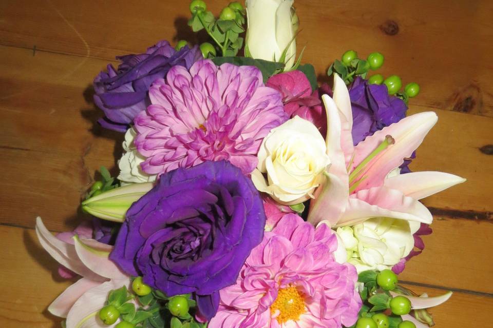 Gorgeous cascading bouquet of lilies, purple lisianthus, escimo roses, green hypericum berries ad lavender dahlias.