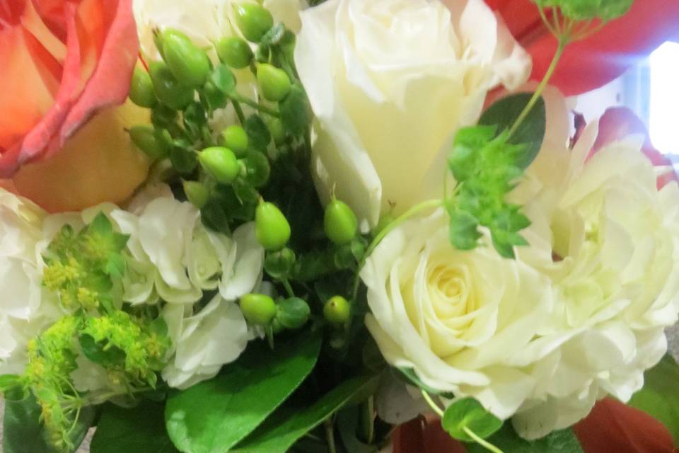 Rustic bouquet of escimo roses, orange asiatic lilies, green hypericum berries, and buplerum and salal. Burlap wrap and family hankey complete this bouquet.