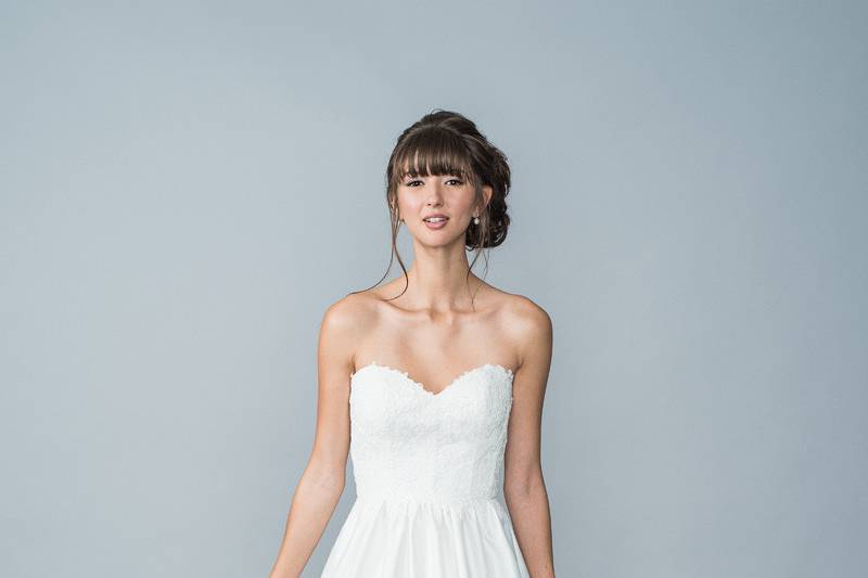 Style Hope <br> Strapless sweetheart neckline, lace appliqué bodice with an illusion back with boning. The skirt is satin embossed, finished with fabric buttons down the train. 