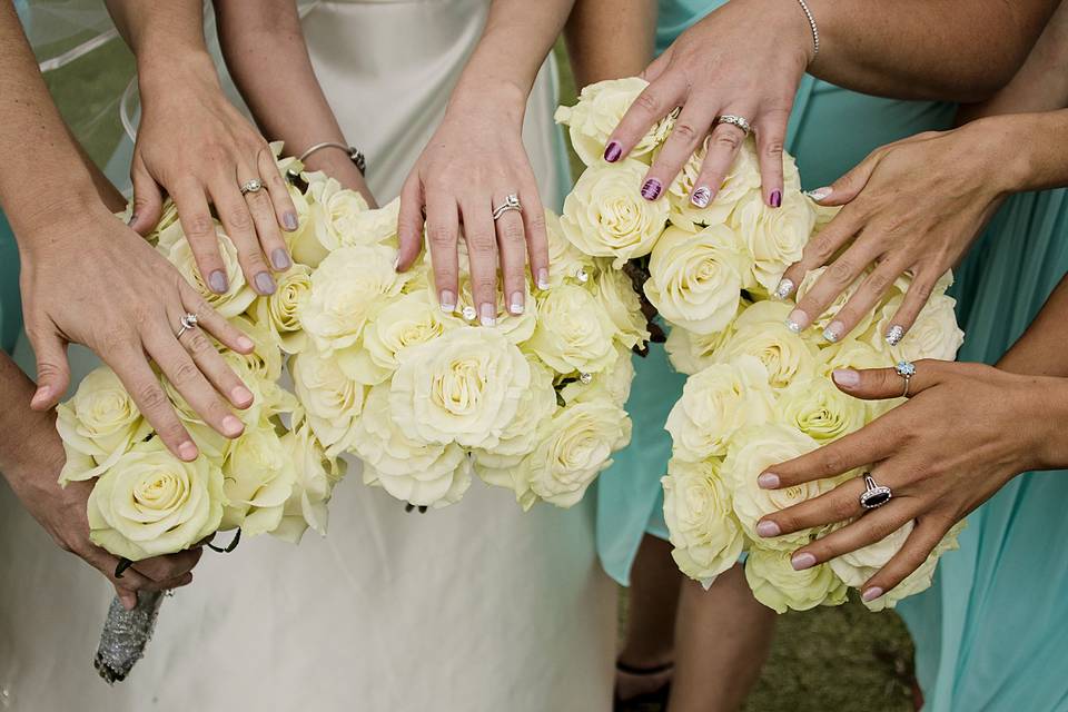 The bride and her bridesmaids with their hands on their bouquets.