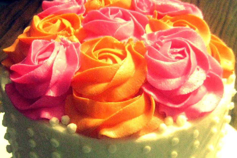 Cutting cake with bright orange and pink buttercream roses