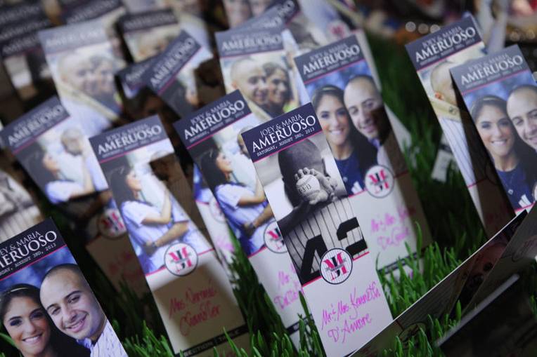 WEDDING ESCORT CARDS
THE TABLE TENT Escort Cards (View from Mike & Kelly’s Big Day)
Our Tent style Escort Cards like you’ve seen before…sort of. Most times this style Escort Cards comes on white paper with pre-formatted simple text. Not this. We design them inside and out. Imagine the outside front with a monogram and on the other side a spot for your guest’s name and table. The inside is where it gets fun. We can place some fun facts about your wedding, fun questions to ask about the Bride and Groom, fun facts about something regarding your theme or even photos of you and yours. This tent style Escort Cards will be a big help for the table of guests that may not know each other very well to start the conversation going!
THE LOVE TICKET Escort Cards (View from Joey & Maria’s Big Day)
Sized at 2″ x 8″ this style Escort Card becomes a quick hit as soon as guests enter Cocktail Hour. The ability to have up to 4 different designs lets you showcase photos of you and your partner. If you g