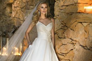 Beauty, style and sophistication. This ball gown wedding dress in French Mikado features a unique v-neckline with delicate straps. Little surprises like pearl buttons, dazzling optional flower accents, and pockets are all accented by a classic full skirt.