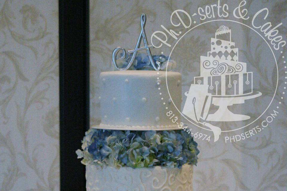 An all-buttercream cake adorned with hand-piped scrollwork and dots.  Cakes were separated by pillars and filled with fresh hydrangea.