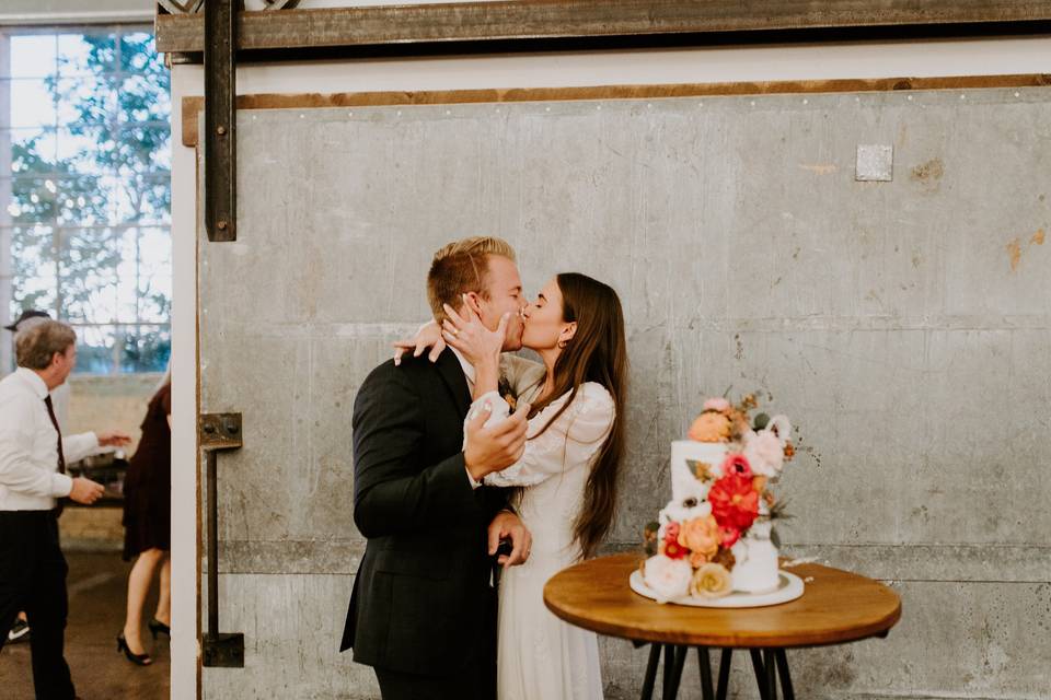 Couple kisses by cake