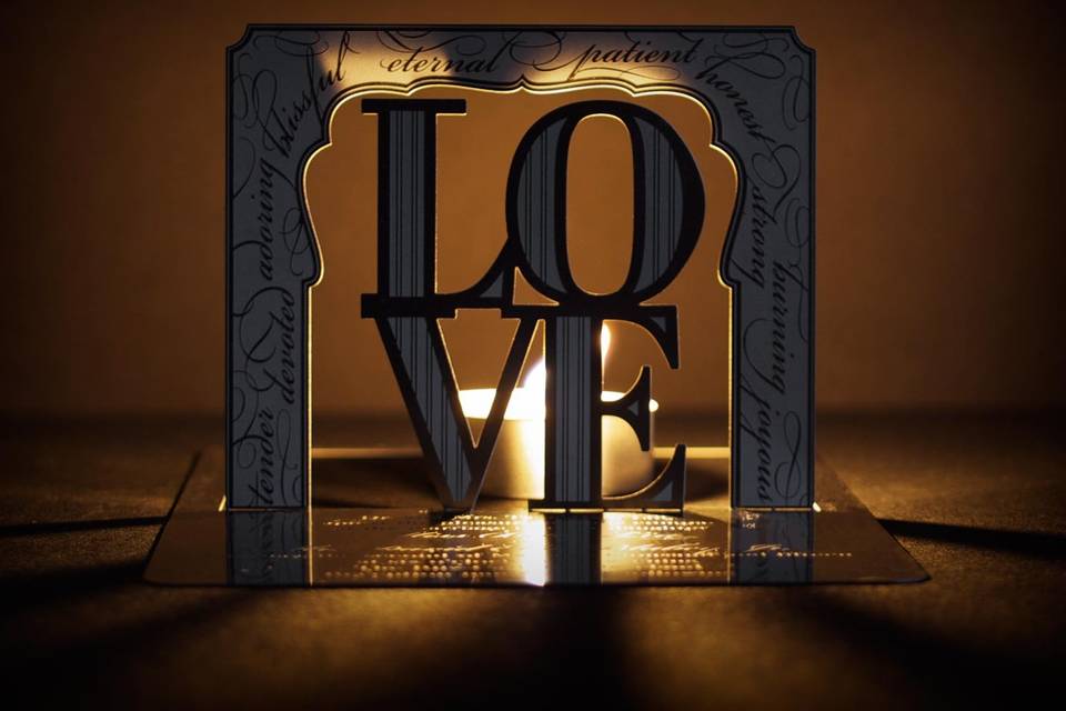 The LOVE metal invitation… love is what brought you together, what led you to this moment, and what you will share with your friends and family. Mails flat and is folded into a sculpture by guests. Folding at the perforations reveals two layers to the sculpture – the first the word “love” and behind it the beautifully ornate border. Place a tea light behind it for beautiful, dancing shadows. Or use as home décor. LOVE is also available as a favor with slits into which an escort card can be inserted.