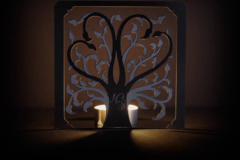 The ROOTS metal invitation… roots are a symbol of where you came from and foundation for where you’re headed. Two hearts in the branches symbolize your union. Mails flat and is folded into a sculpture by guests. Folding the invitation at the perforations will allow the tree to stand and the branches to be sculpted – each sculpture will be as unique as your guests. Place a tea light behind the sculpture for beautiful, dancing shadows. Or use as home décor. ROOTS is also available as a favor with slits into which an escort card can be inserted.