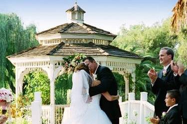 Bride and groom kissing near the gazebo at the end of the ceremony.