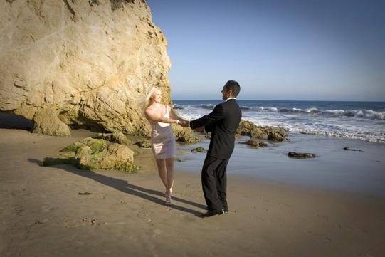 Just married couple frolic on beach.