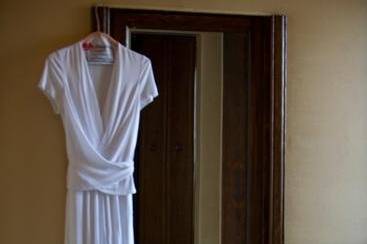 Wedding dress hung next to mirror with shoes in background.