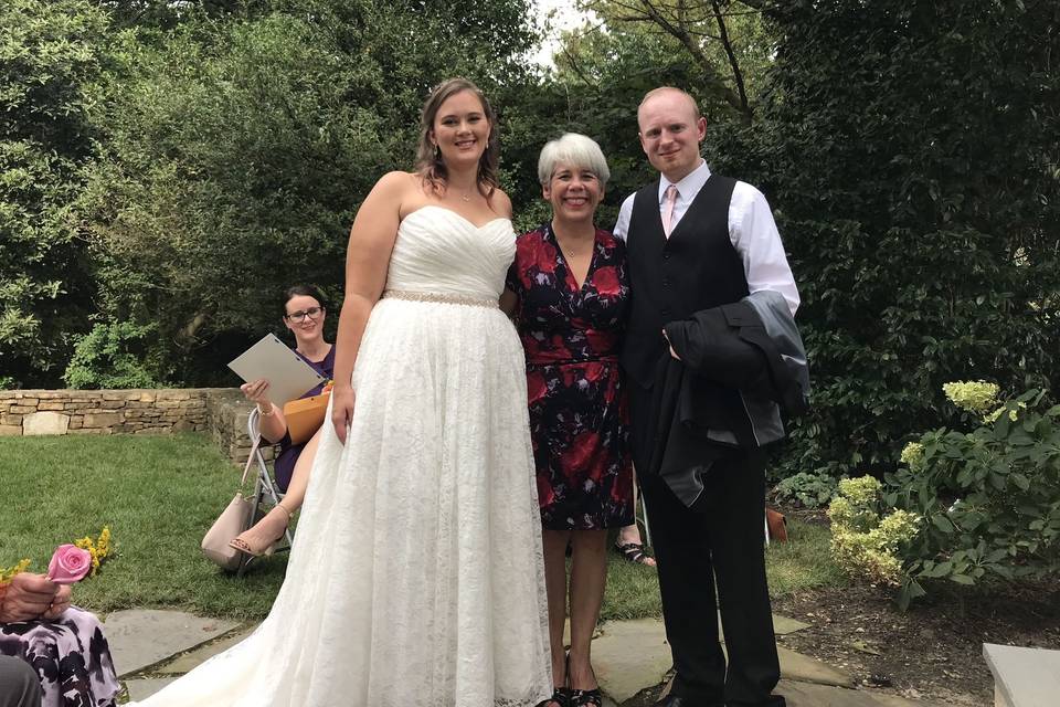 The newlyweds posing with the wedding officiant