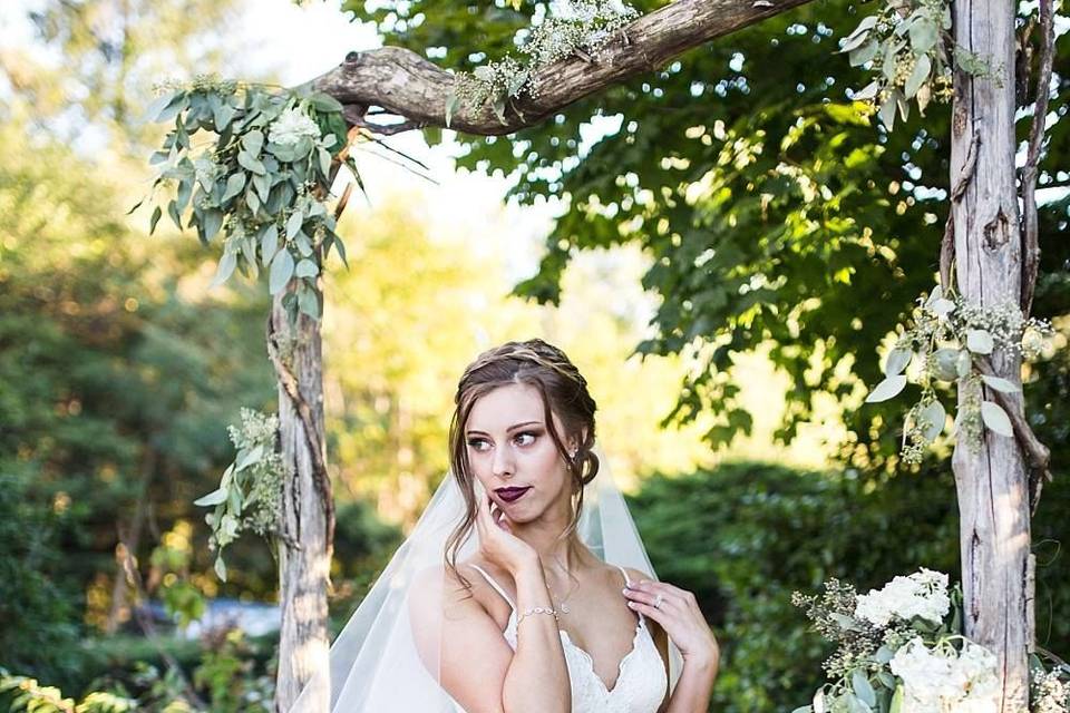 Bride poses under arch