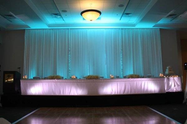 16' Head table drapery treatment highlighted with Tiffany Blue lighting. Head table and cake table highlighted with white lighting.