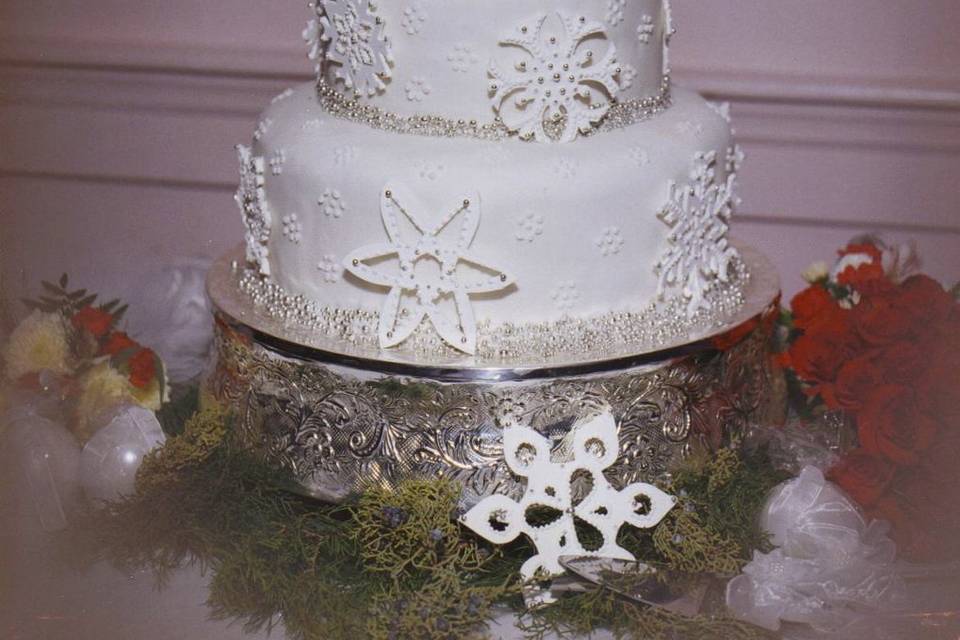 Gorgeous gum paste snowflakes adorn this cake. Each snowflake decorated with royal icing and silver dragees. Silver dragees around base of each cake for lots of sparkle!