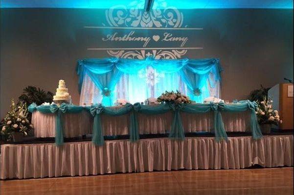 Beautiful wedding at Ala Moana Hotel located in Honolulu, Hawaii. We did the back drop and dressed the wedding party table.  Here were used our white rose embossed backdrop with our tiffany blue accent swagged backdrop. For the table used is our tiffany blue swagged organza with organza bow.