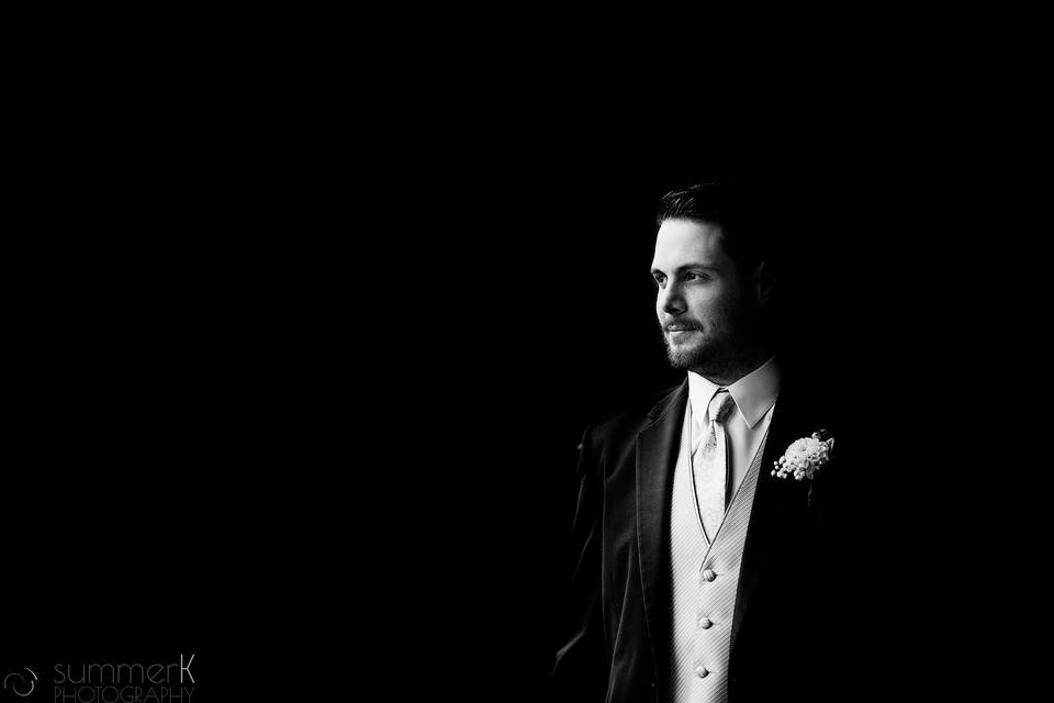 Black and white photo of groom with boutonniere of creamy ivory dahlia and baby's breath.