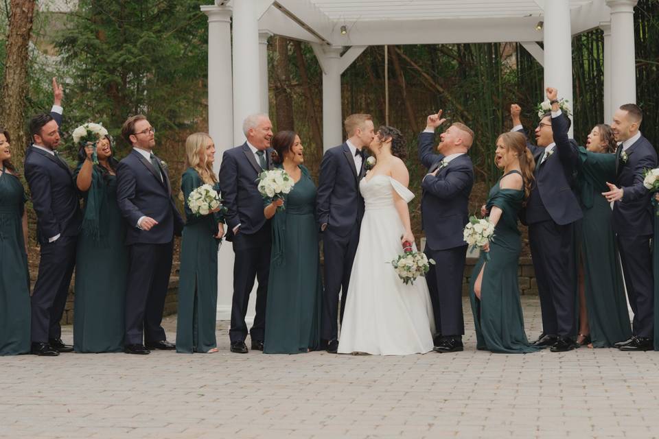 Bridal party cheers for kiss.