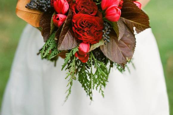 Red cabbage roses, hydrangea leaves, red tulips, and red berry were used to create this bouquet. Photography by Anne Robert.