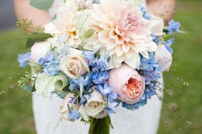 Cafe au lait dahlias, swamp lily, blue delphinium, blue hydrangea, ornamental grasses, and peach cabbage roses were used to create this bouquet. Photography by Carolina Photo Smith