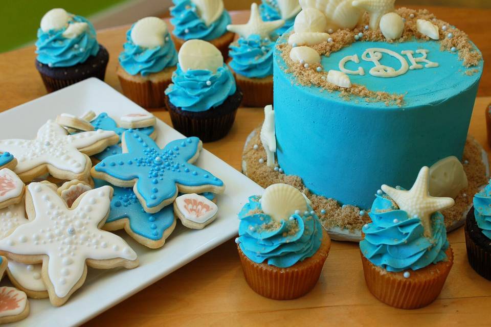Teal beach-themed wedding cake with cupcakes and cookies