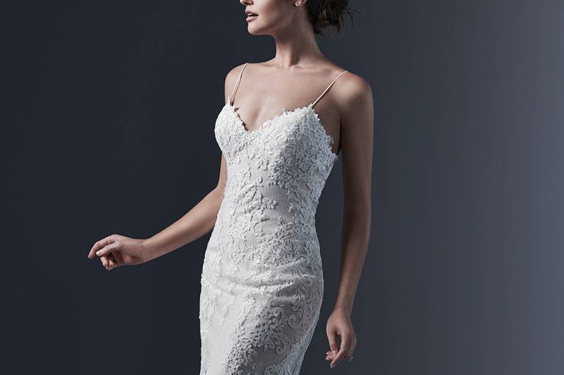 Mattea  <br> Refined elegance is found in this chic lace sheath wedding dress, accented with sexy spaghetti straps, demure illusion back and V-neckline. Finished with pearl buttons and zipper closure.