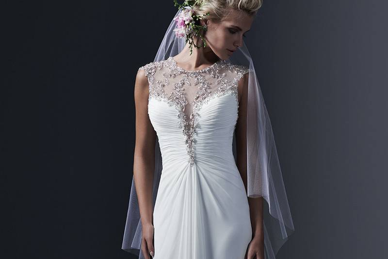 Cara Lynette <br> Swarovski crystals and pearls adorn illusion beading in this elegant sheath wedding dress, available in Paris chiffon or tulle, with plunging illusion front and back neckline, encrusted with crystals. Finished with crystal buttons over zipper closure.