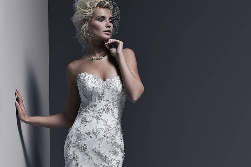 Gintare<br> A timeless and sophisticated style, this Chantilly lace fit and flare wedding dress is sweetened with lavish Swarovski crystal beaded lace motifs adorning the bodice and skirt, and edging the hemline. Finished with corset or covered buttons and zipper over inner corset back closure.