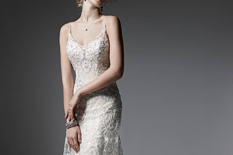 Style Venecia <br> Elegant lace and tulle, Swarovski crystals, and pearls combine to create this breathtaking sheath wedding dress, with sexy beaded spaghetti straps, and an alluring, illusion back. Finished with deep illusion sweetheart neckline and crystal buttons over zipper closure.