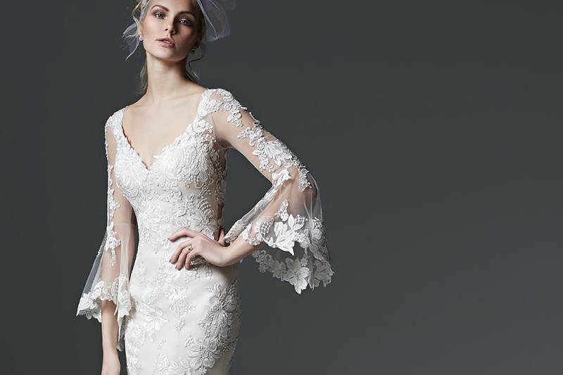 Style Gabriella <br> Bohemian beauty is found in this lace sheath wedding dress with gorgeous, illusion lace poet sleeves and a dramatic illusion back. Finished with pearl buttons over zipper closure.