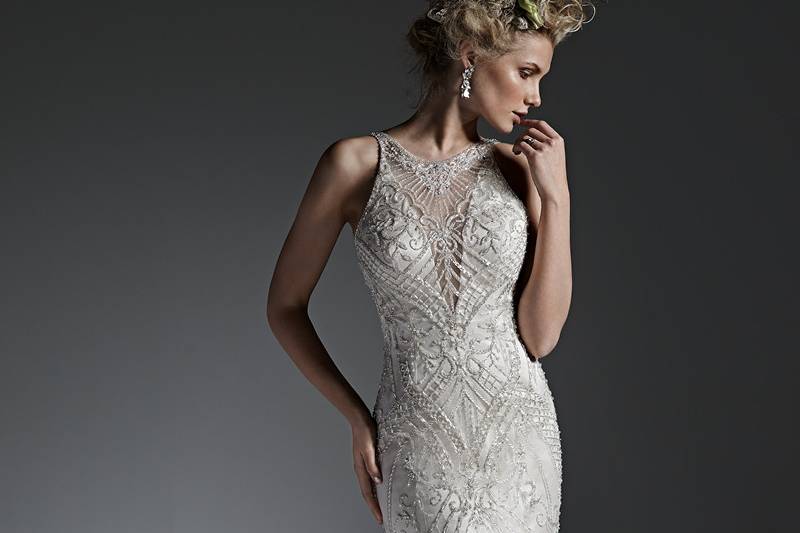 Style Maui <br> Understated glamour is found in this sultry sheath wedding dress, with intricate patterns of sparkling beading and shimmering Swarovski crystals adorning the bodice and plunging illusion neckline. Finished with open back and crystal buttons over zipper closure.