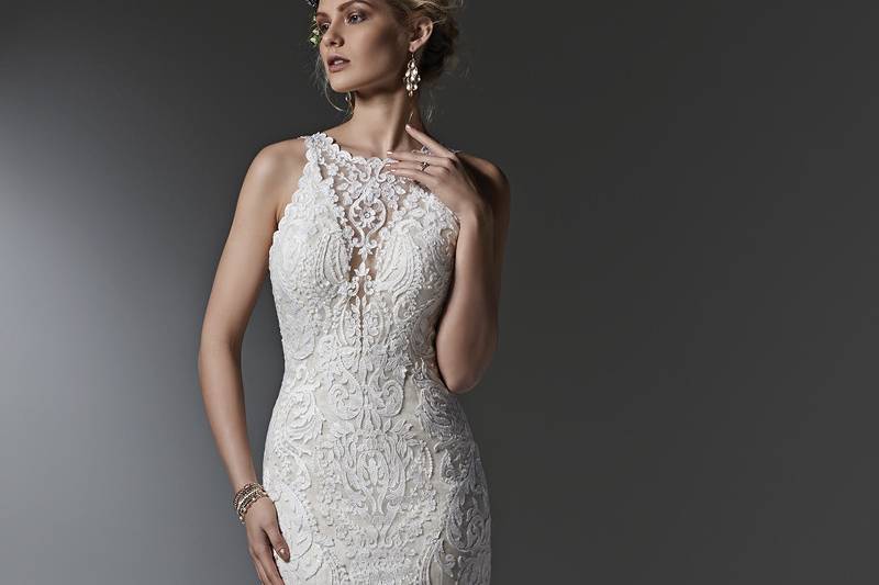 Style Winifred <br> Timeless and elegant, this lace sheath wedding dress features a modern illusion deep V halter neckline, a stunning, scalloped plunging back, and illusion straps. Finished with covered buttons over zipper closure.