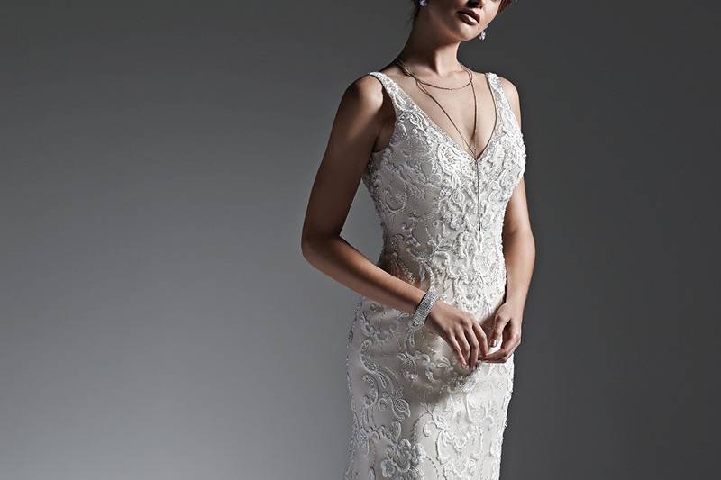 Style River <br> Romantic lace and tulle combine to create this striking sheath wedding dress, accented with glittering Swarovski crystals and shimmering beads. Finished with V-neckline, plunging back and covered buttons over zipper closure.