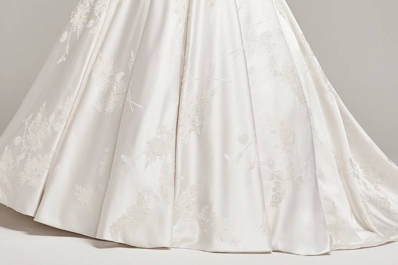 Essex<br> Dramatically structured, this luxurious brocade ball gown, with sweetheart neckline, pockets and natural waist, features lightly beaded details and belt. Finished with a stunning full train and covered buttons over zipper and inner elastic closure.