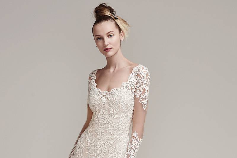 Melrose <br> Modern lace appliqués adorn the illusion long sleeves, fitted bodice, and scalloped hemline of this crosshatch tulle over jersey fit and flare wedding dress. Complete with illusion sweetheart neckline, double illusion keyhole back, and dramatically sweeping train. Finished with crystal buttons and zipper closure.