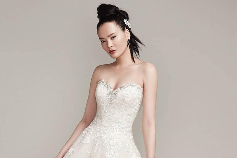 Olga <br> Swarovski crystals trace the sweetheart neckline of this breathtaking lace and tulle ball gown with natural waist. Finished with crystal buttons over zipper and inner corset closure.