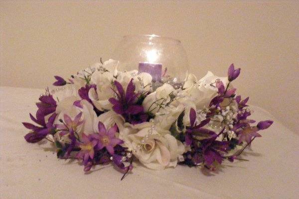 Another popular centerpiece with the glass bowl and crystal fillers with a candle in the middle...done in white carnations and purple accent flowers