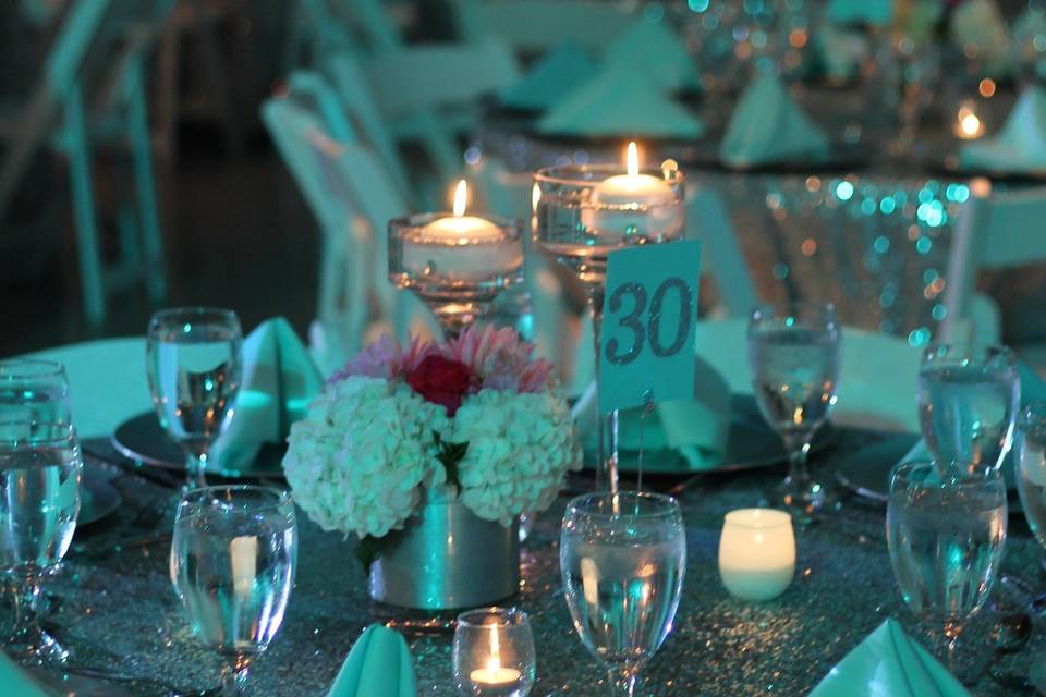 Simple floral centerpieces with candles on top of our beautiful sequin linens.